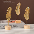 Skulptur med bladmotiv i metal på træfod til indendørs brug