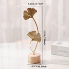 Skulptur med bladmotiv i metal på træfod til indendørs brug