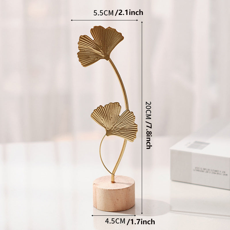 Skulptur med bladmotiv i metal på træfod til indendørs brug