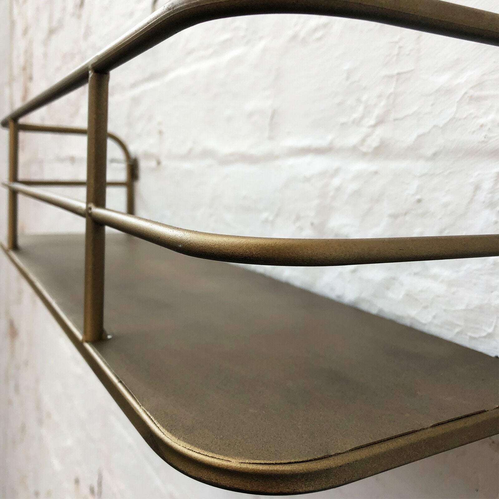 Væghylde i metal med guldfinish til indendørs brug